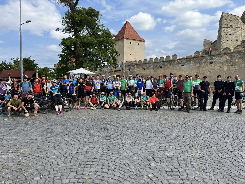 Group photo of participants at the second edition of the Carpathia Bike Tour, standing in front of Rupea Fortress in Romania